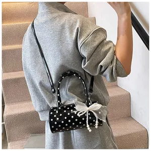 Polished polka dot Boston bag detail with white lace bow and elegant pearl tassel charm