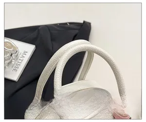 Close-up of white lychee leather texture and pink bag charm with silver zipper details