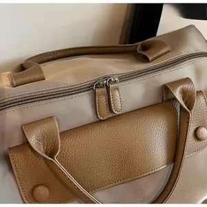 Close-up of khaki oxford fabric and brown leather stitching on a fitness travel bag