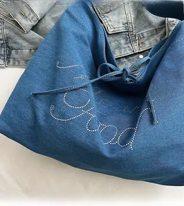 Detail of blue denim tote bag with white polka dot lettering and tie-strap closure
