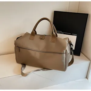 Close-up of khaki travel bag with leather handles and metallic zippers on marble