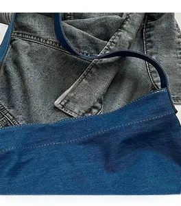 Detailed close-up of reinforced stitching and twill texture on denim shoulder bag