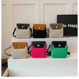 Detail of multi-color canvas and leather crossbody bags with metal buckle closure