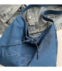 Detail of denim tote bag showing rhinestone letter pattern and side drawstring design