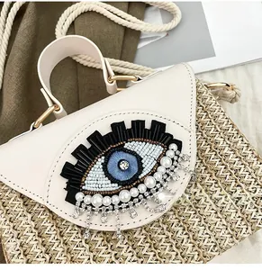 Macro shot of evil eye beadwork and crystal tassels on a woven straw bag