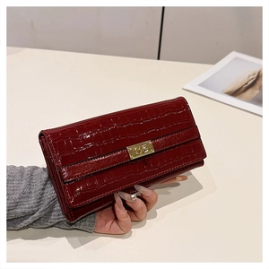 Détail d'un portefeuille bordeaux motif crocodile avec fermoir rotatif doré élégant