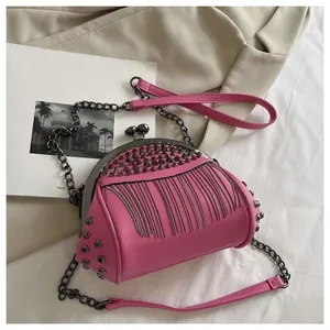 Detail of pink shell crossbody bag with silver cone rivets and metal chain tassels