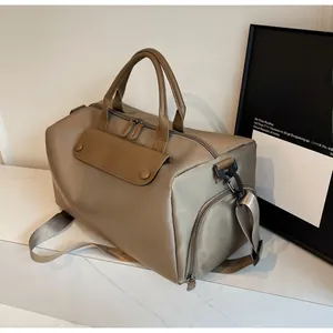 Detail view of khaki travel bag with leather accents and side pockets on marble