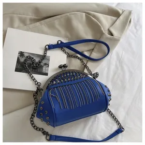 Detail of royal blue leather bag with silver rivets, metal tassels, and chain strap