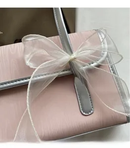 Dettaglio della borsa rosa chiaro con trama verticale, finiture argento e grande fiocco in garza