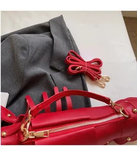 Detail of smooth adjustable red faux leather shoulder strap with golden metal hardware