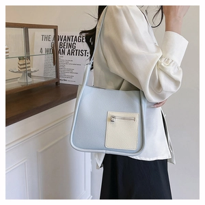 Detail of light blue crossbody bag with white zip pocket and pebble leather texture