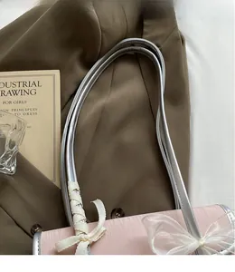 Dettaglio borsa rosa con tracolla argentata liscia e fiocco decorativo in pizzo