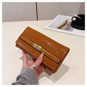 Gros plan sur la pochette en cuir croco marron caramel avec fermoir doré élégant