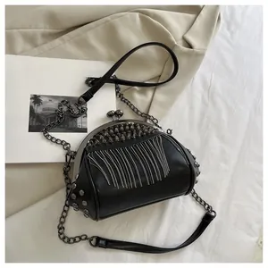 Detail of black punk crossbody bag with silver studs and long metal chain tassels