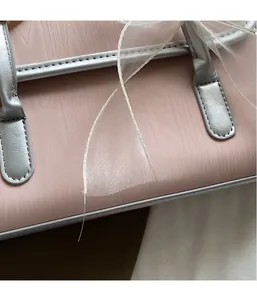 Dettaglio borsa in ecopelle rosa testurizzata con fiocco in organza e manico in metallo