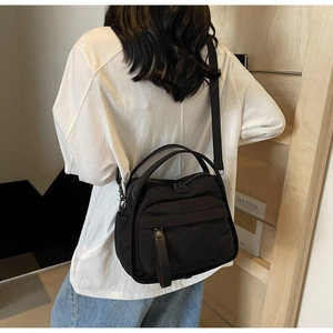 Detail of minimalist black nylon crossbody bag with zipper pocket and fabric strap