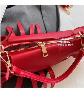 Detail of red leather lobster bag featuring a smooth gold metal zipper and strap buckle