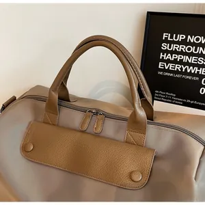 Detail of khaki oxford cloth travel bag with brown leather handles and dual zippers