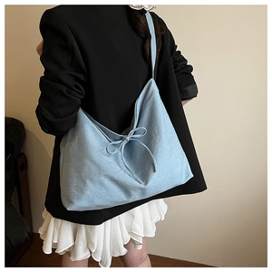 Light blue denim tote bag with bow detail and sequins shown on a model for daily use