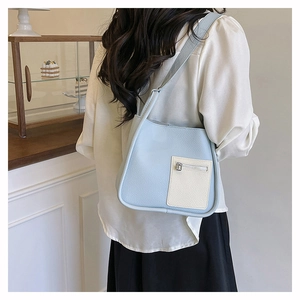 Detail shot of light blue pebbled leather square shoulder bag with white accent pocket