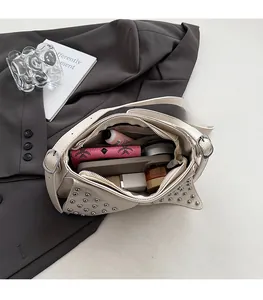 Internal view of a white rivet shoulder bag showing spacious dual compartments and storage