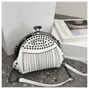 Detail of white studded shell bag with metallic tassel fringe and retro clip closure