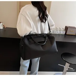 Rear view of a model wearing a black nylon sports bag with leather handles in a room