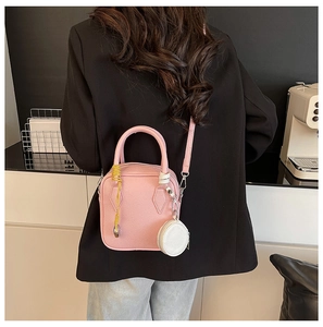 Detailed back view of model carrying pink litchi leather mini handbag with accessories