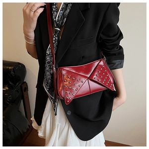 Détail du sac rouge à clous argentés et rabat géométrique porté par un mannequin