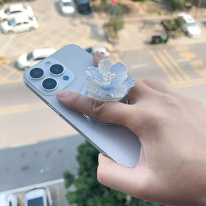 Magnetic flower phone grip with blue gradient petals and pearl accents on a smartphone