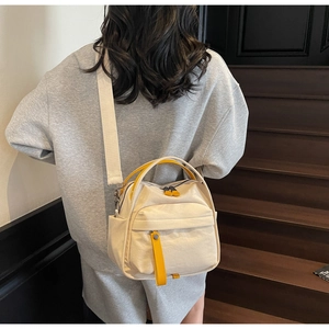 Detail of minimalist cream canvas crossbody bag with bright yellow handles and wide strap