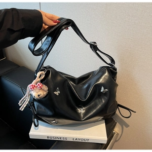 Detail of black hobo bag with silver butterfly hardware and adjustable wide shoulder strap