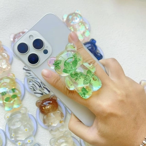 Macro detail of translucent bear phone grip featuring embedded green leaf decorations