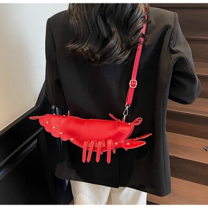Detail of red lobster-shaped crossbody bag with gold rivets worn on model back