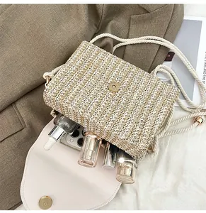 Detail view of woven straw crossbody bag interior holding phone and cosmetics