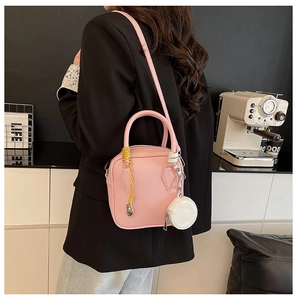Pink lychee texture crossbody bag with round coin purse charm shown on model