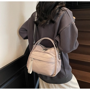 Rear view of a model carrying the pale pink nylon crossbody bag on a wooden staircase