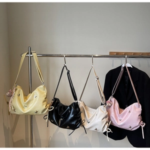 Detail of four colorful pleated crossbody bags with butterfly embroidery and plush charms