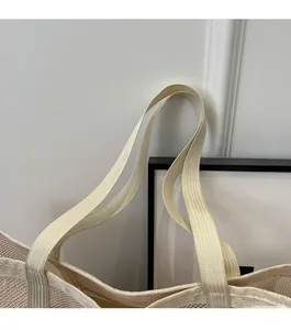 Detail of reinforced woven straps and mesh texture on a beige summer tote beach bag