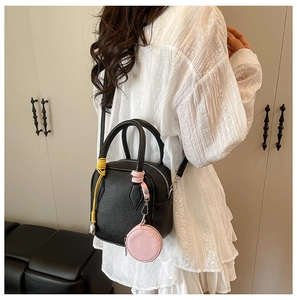 Detail of black pebbled leather crossbody bag with pink coin purse and yellow cord