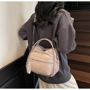 Back view of model wearing a light pink nylon crossbody bag on a wooden staircase