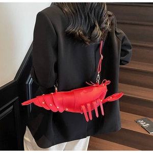 Detailed view of red lobster shaped crossbody bag with gold rivet accents on a model