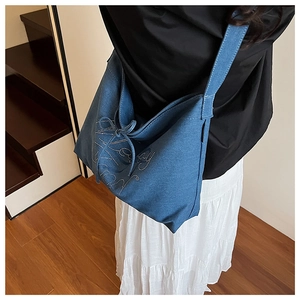 Detail of blue denim tote bag featuring rhinestone lettering and bow decoration