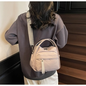 Close-up of a lightweight nylon crossbody bag with wide straps shown on a model