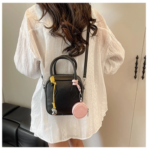 Detail of black pebbled leather mini crossbody bag with colorful woven rope and charm