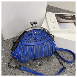 Detail of royal blue leather crossbody bag with metal rivets and tassel chain fringe
