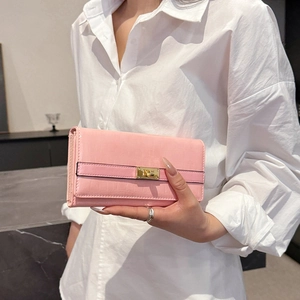 Portefeuille long rose à motif crocodile avec fermoir doré en métal tenu à la main