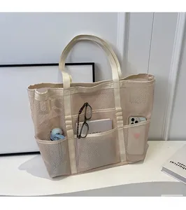 Detail of off-white mesh tote bag showing multi-pocket storage and breathable mesh texture