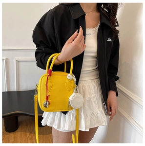 Close-up of a yellow pebbled leather handbag with round white coin purse and tassel